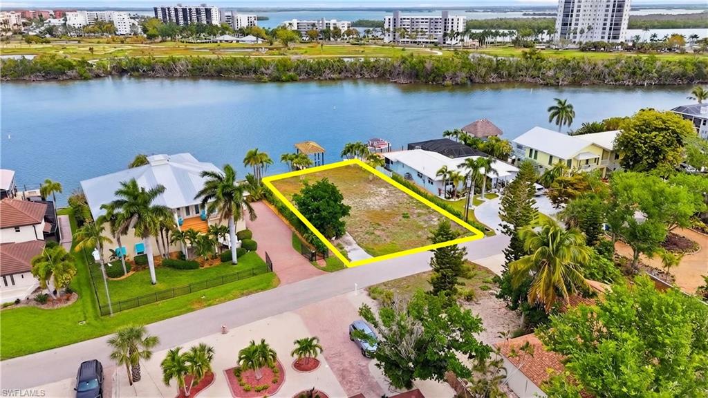 View of urban area with property parcel outlined and a nearby body of water - Virtually Edited Image