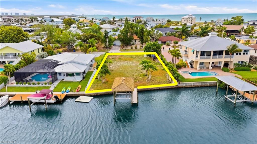 Aerial view of residential area with a large body of water and property parcel outlined - Virtually Edited Image