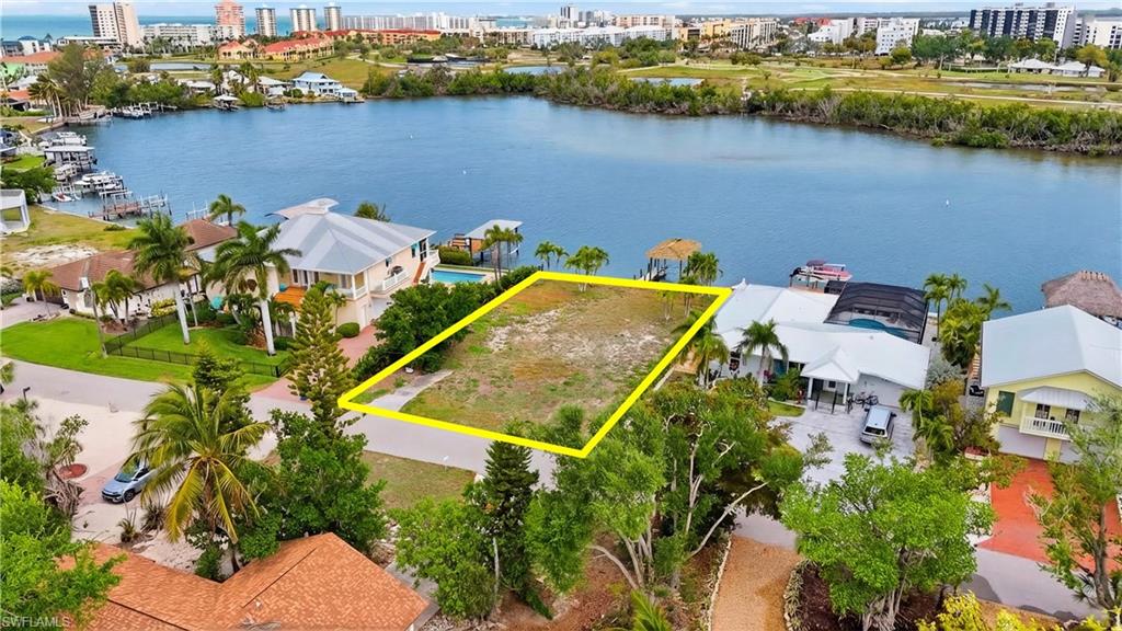 View of urban area with property parcel outlined and a large body of water - Virtually Edited Image