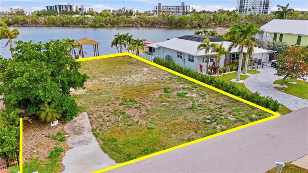 View of urban area with property boundaries highlighted and a nearby body of water - Virtually Edited Image