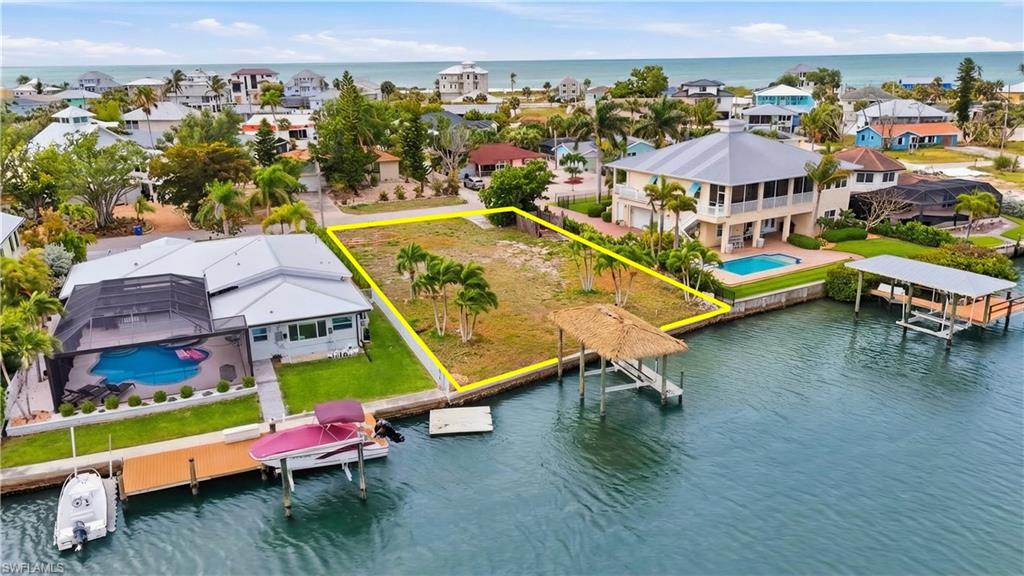 Aerial perspective of suburban area featuring a large body of water and property parcel outlined - Virtually Edited Image