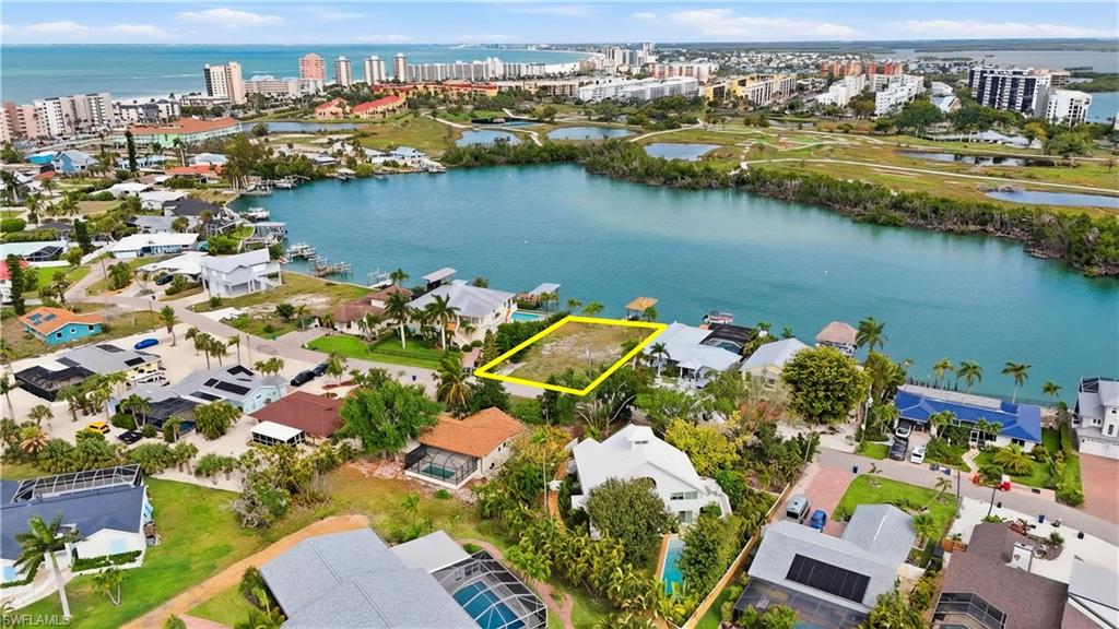 View of urban area with property parcel outlined, a nearby body of water, and nearby suburban area - Virtually Edited Image
