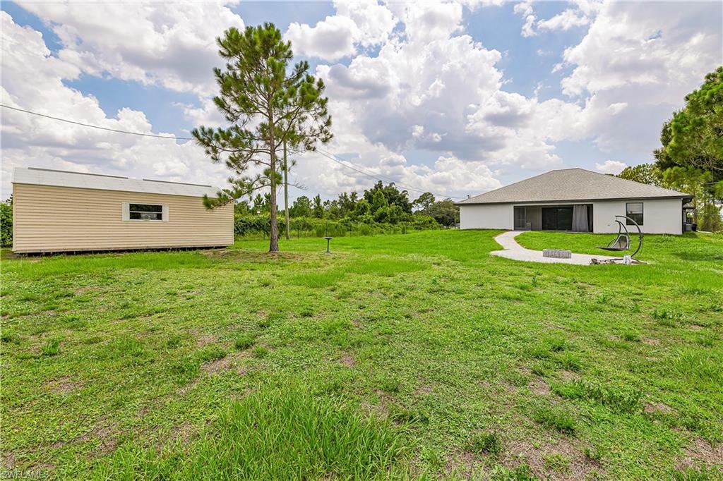 Expansive green space featuring a detached auxiliary structure with horizontal siding and a rectangular window