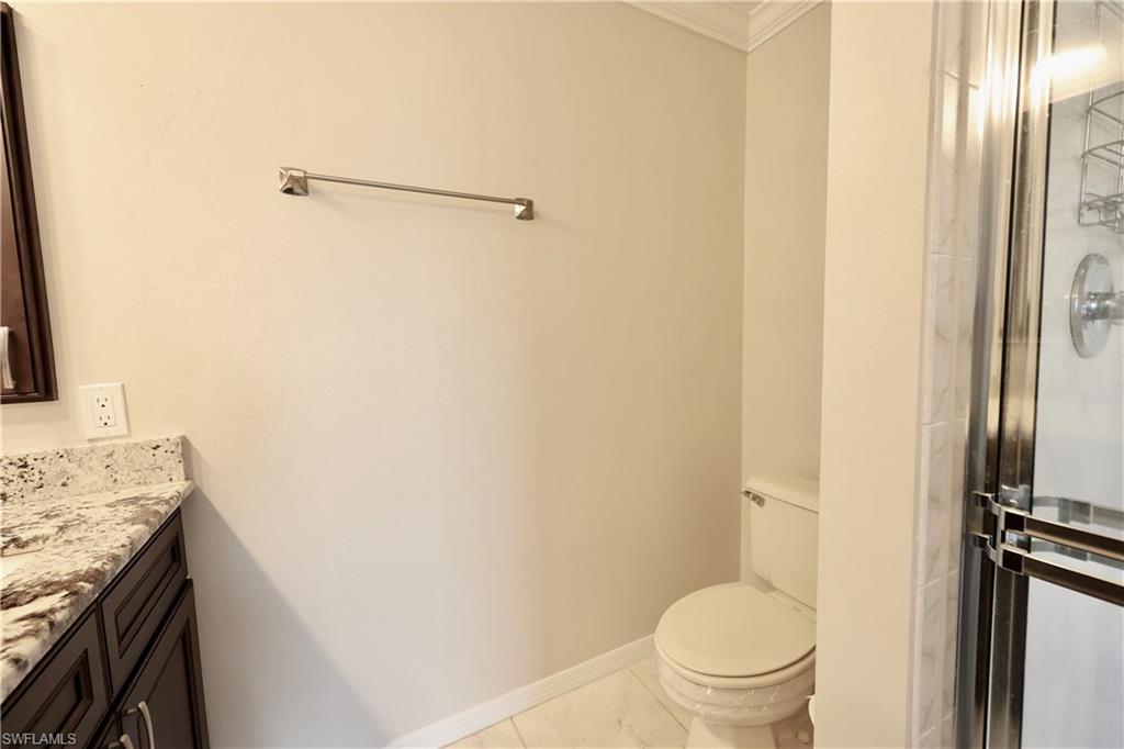 Full bath with vanity, a shower stall, ornamental molding, and light marble finish flooring