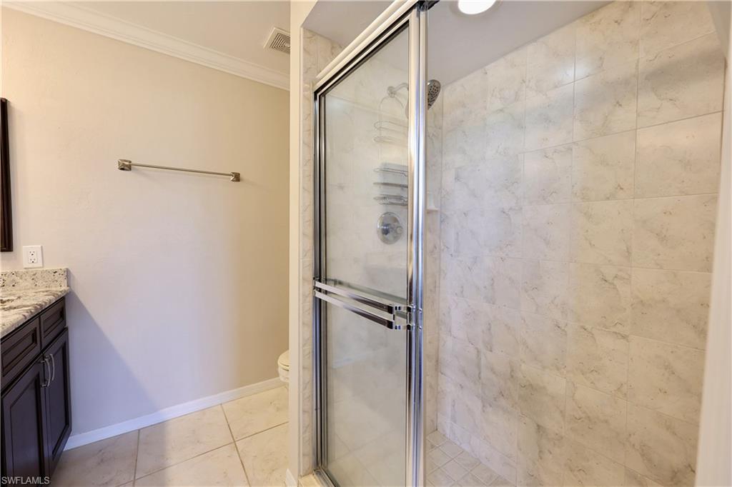 Full bathroom with vanity, crown molding, a shower stall, and light tile patterned floors