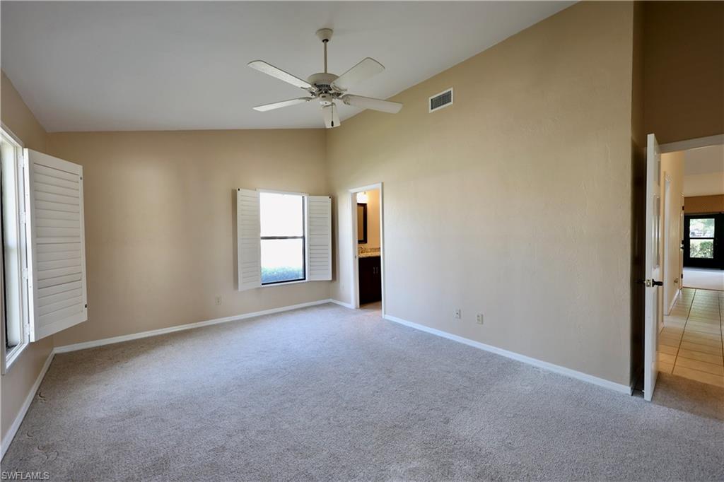 Unfurnished bedroom with light colored carpet, lofted ceiling, a ceiling fan, and ensuite bath