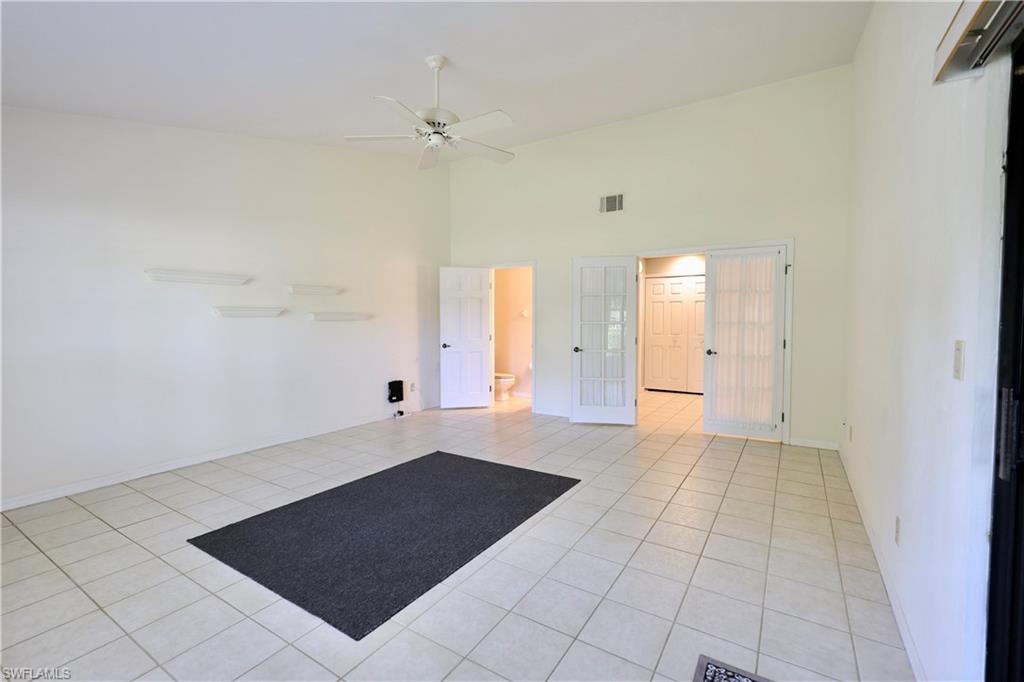 Spare room with a high ceiling, light tile patterned floors, ceiling fan, and french doors
