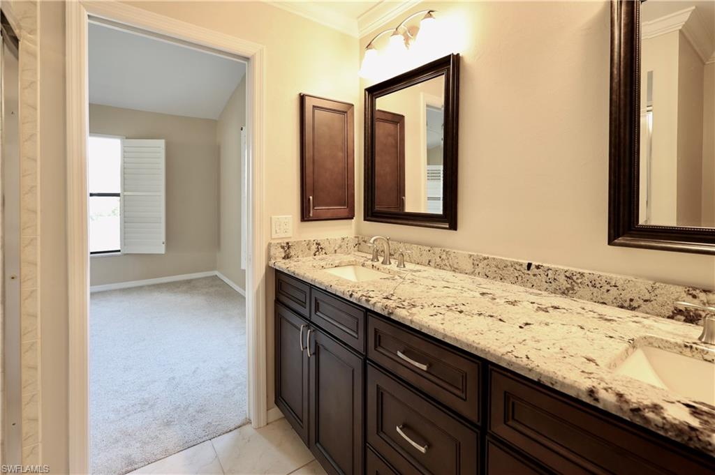 Bathroom with crown molding, double vanity, and light colored carpet