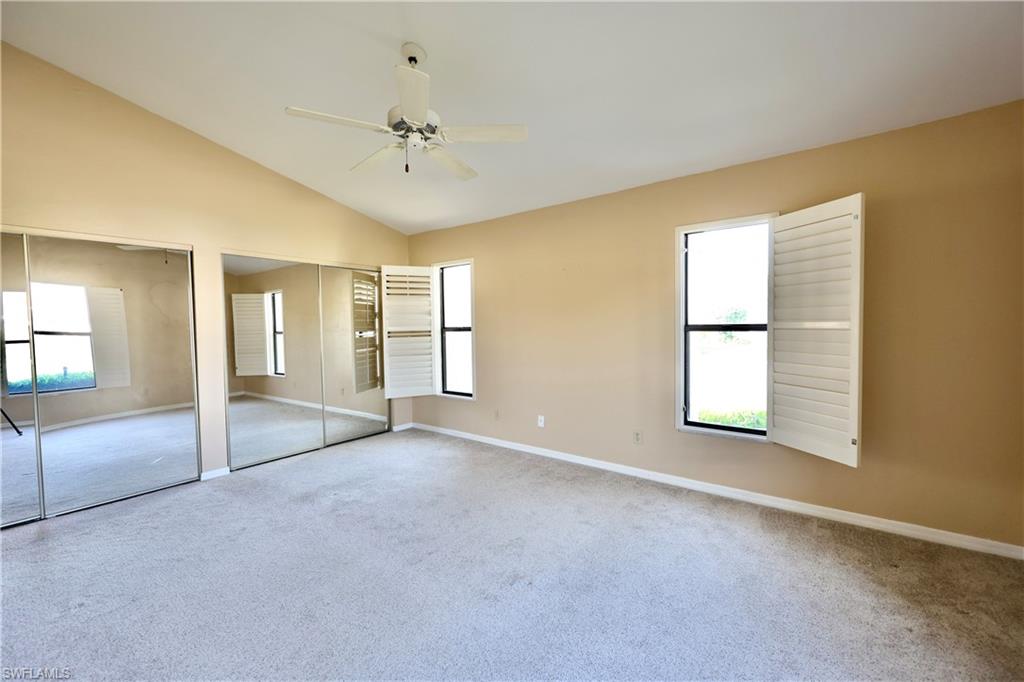 Unfurnished bedroom with two closets, light carpet, a ceiling fan, and vaulted ceiling