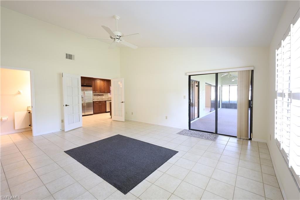 Unfurnished living room with a ceiling fan, french doors, lofted ceiling, and light tile patterned floors