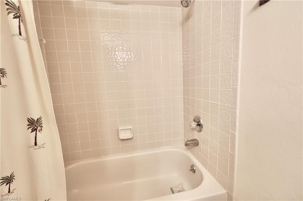 Bathroom with shower / tub combo with curtain and a textured wall
