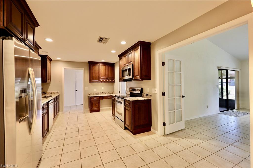 Kitchen with stainless steel appliances, light tile patterned flooring, recessed lighting, and light stone countertops