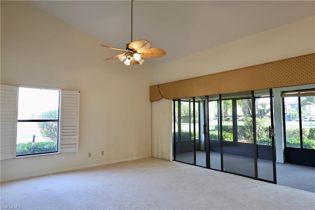 Carpeted empty room with ceiling fan and lofted ceiling