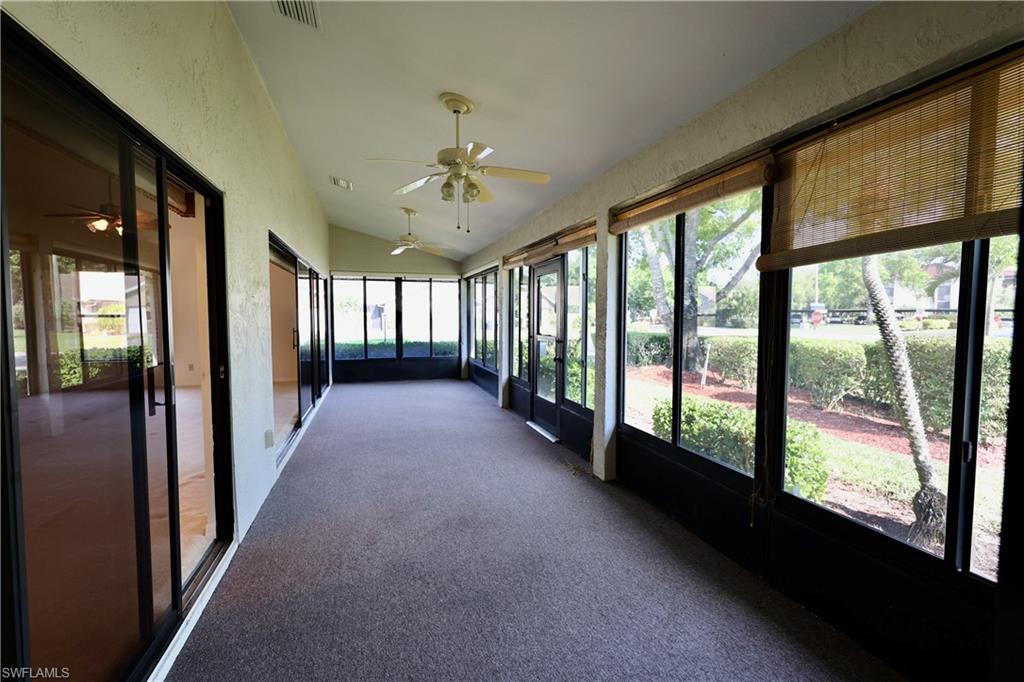 Unfurnished sunroom featuring ceiling fan, vaulted ceiling, and healthy amount of natural light