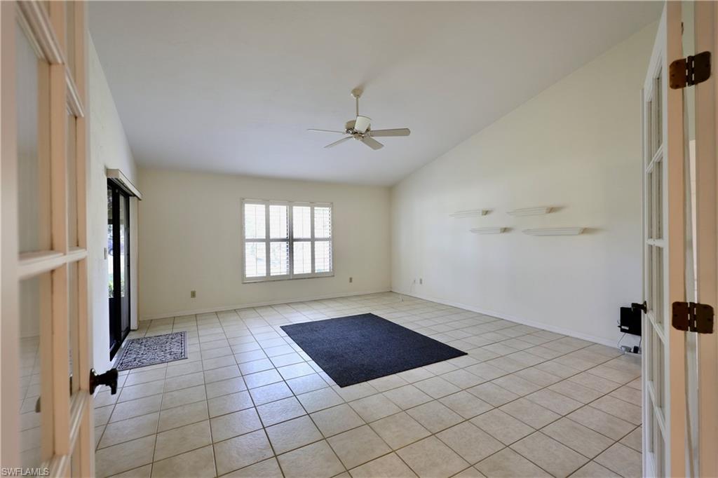 Unfurnished room featuring lofted ceiling, a ceiling fan, light tile patterned floors, and french doors