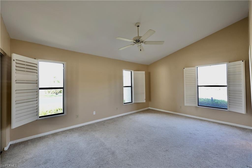 Unfurnished room with a ceiling fan, light carpet, healthy amount of natural light, and vaulted ceiling