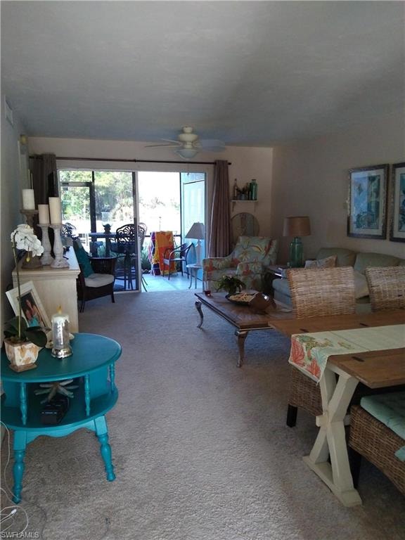 Living area with a ceiling fan, plenty of natural light, and carpet