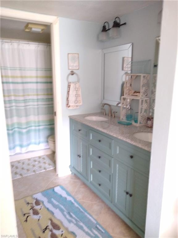 Full bath featuring double vanity, curtained shower, and light tile patterned flooring