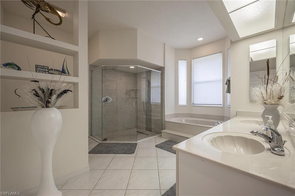 Bathroom with a bath, a shower stall, light tile patterned flooring, and double vanity