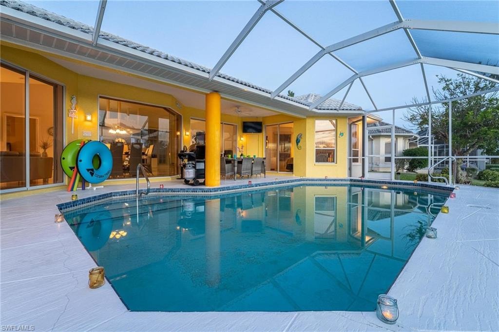 Swimming pool with a sunroom, glass enclosure, a patio, and outdoor dining area