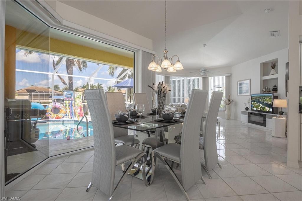 Dining area featuring a chandelier, light tile patterned flooring, and a ceiling fan