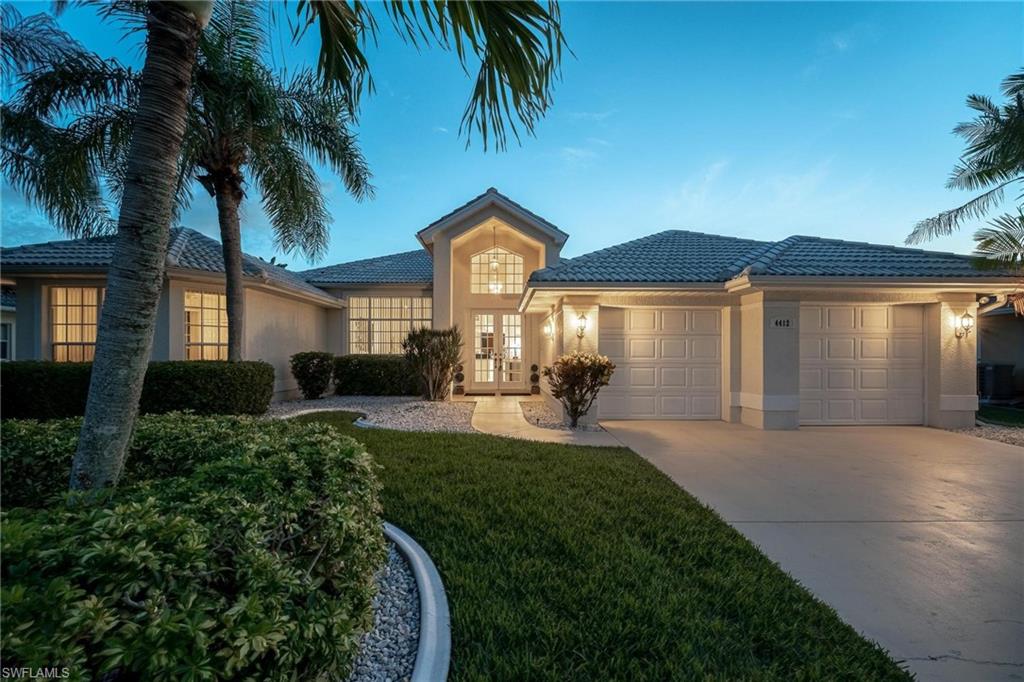 Single story home with french doors, an attached garage, concrete driveway, stucco siding, and a front lawn