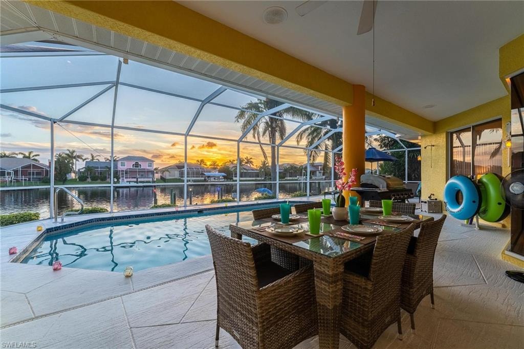 Pool at dusk with a patio, a sunroom, an outdoor pool, and glass enclosure