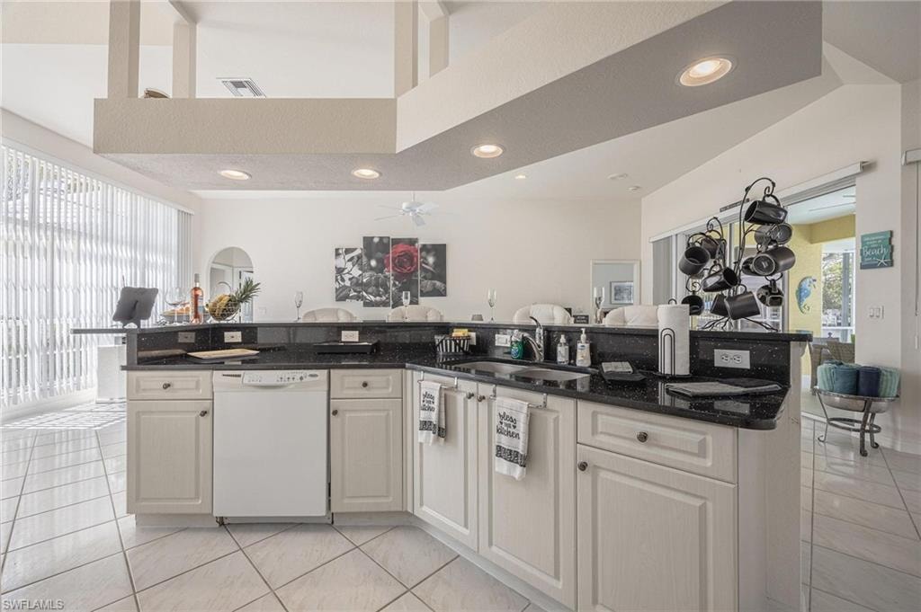 Kitchen with open floor plan, dark stone counters, light tile patterned floors, a high ceiling, and recessed lighting