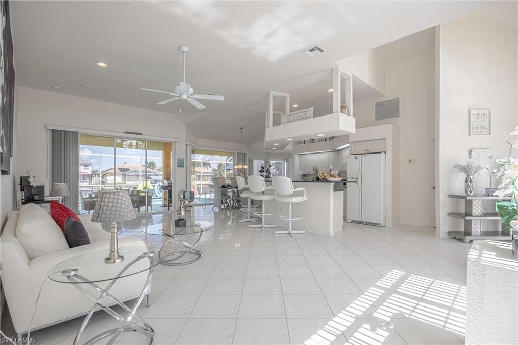 Living room with ceiling fan, recessed lighting, light tile patterned floors, and lofted ceiling