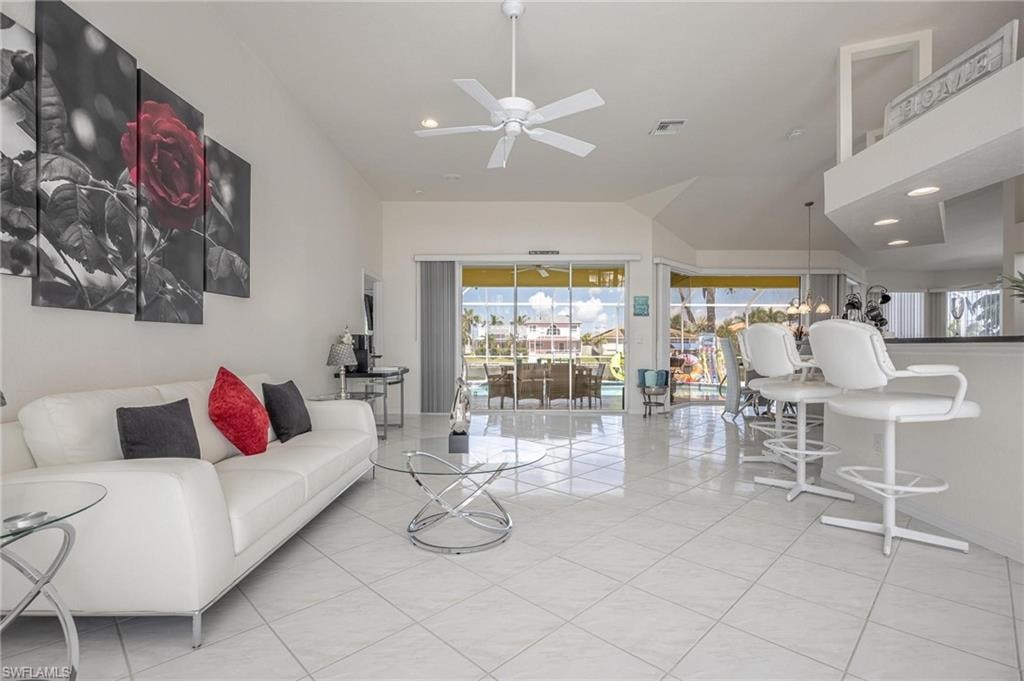 Living room with ceiling fan, recessed lighting, light tile patterned flooring, and vaulted ceiling