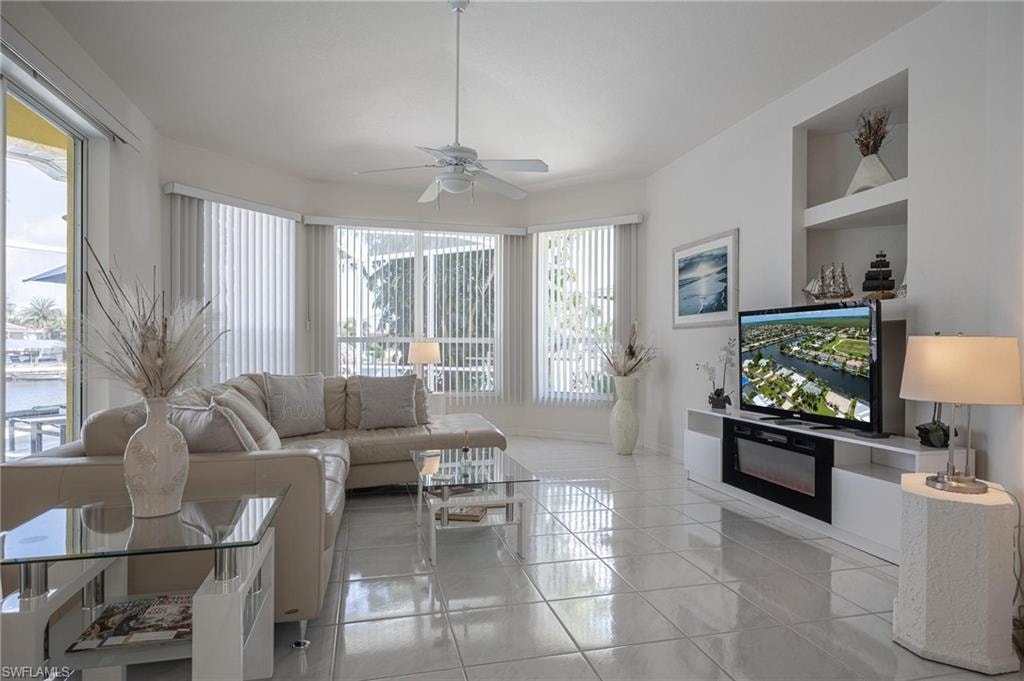 Living area featuring a ceiling fan, light tile patterned flooring, and built in shelves