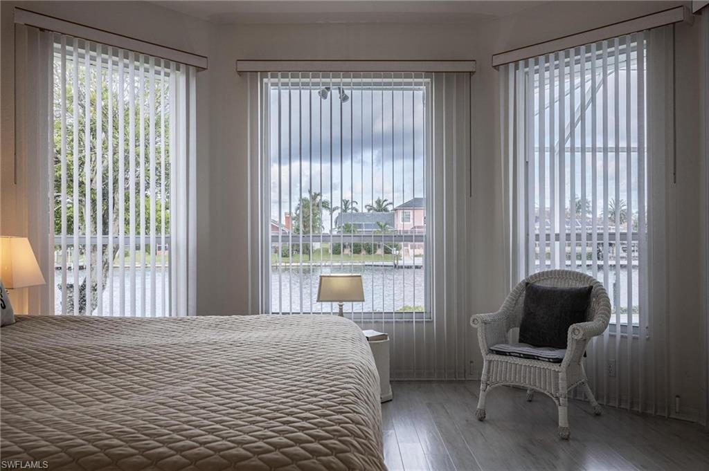 Bedroom with multiple windows, wood finished floors, and a residential view