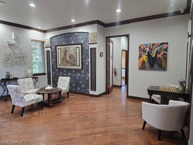 Sitting room with wood-type flooring, crown molding, and recessed lighting