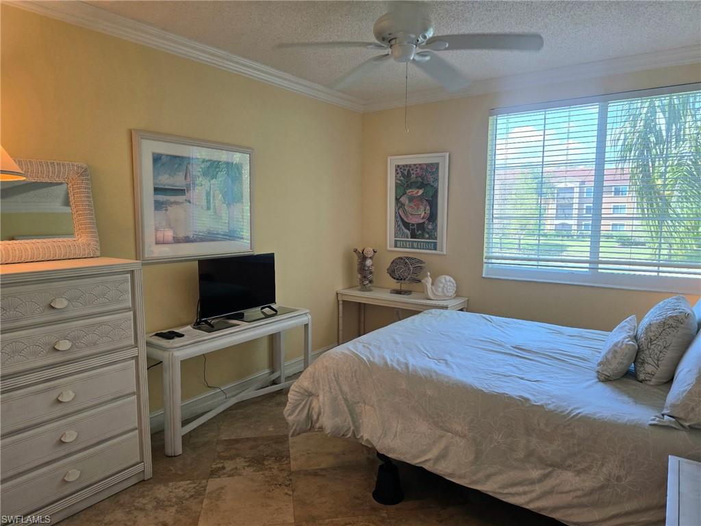 Bedroom featuring ornamental molding, ceiling fan, and a textured ceiling