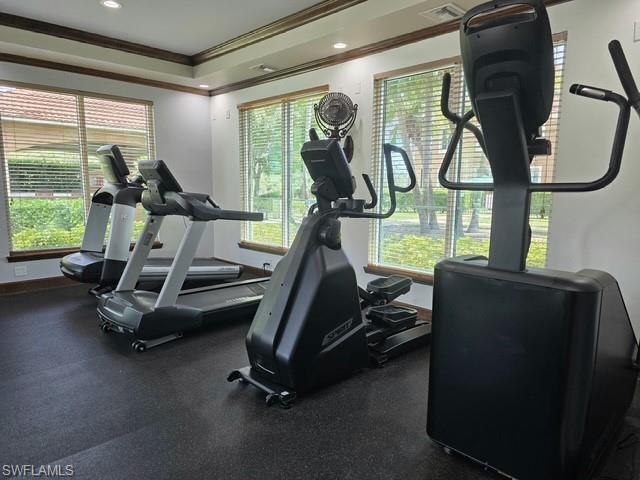 Workout area with ornamental molding, a raised ceiling, and recessed lighting