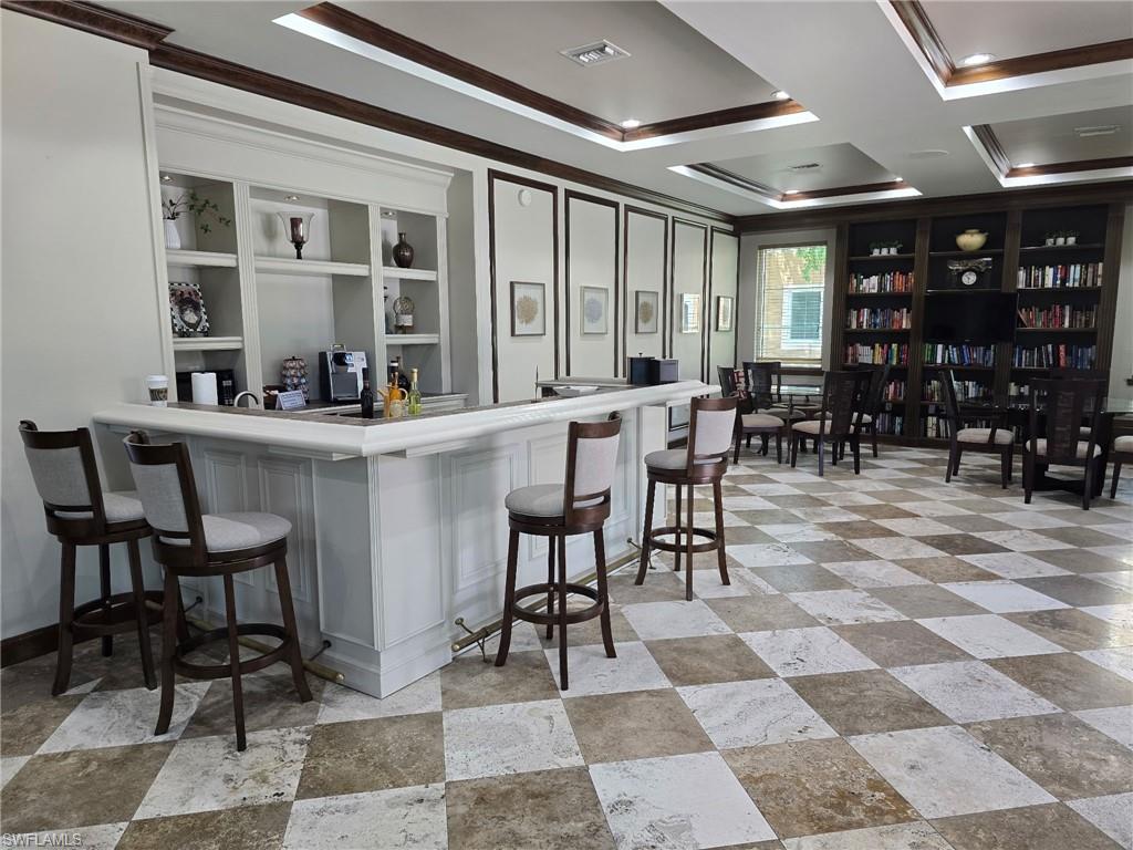 Bar area with crown molding, coffered ceiling, light countertops, and open shelves