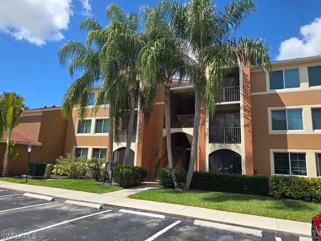 View of apartment building / complex with uncovered parking