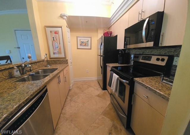 Kitchen with stainless steel appliances, crown molding, dark stone counters, and a peninsula