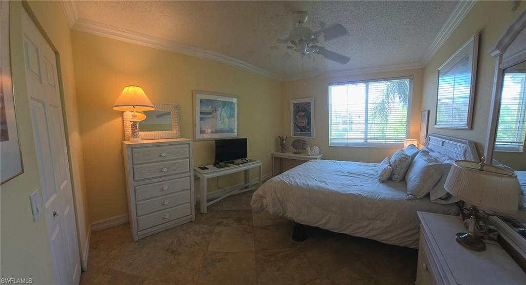 Bedroom with a textured ceiling, ornamental molding, and ceiling fan
