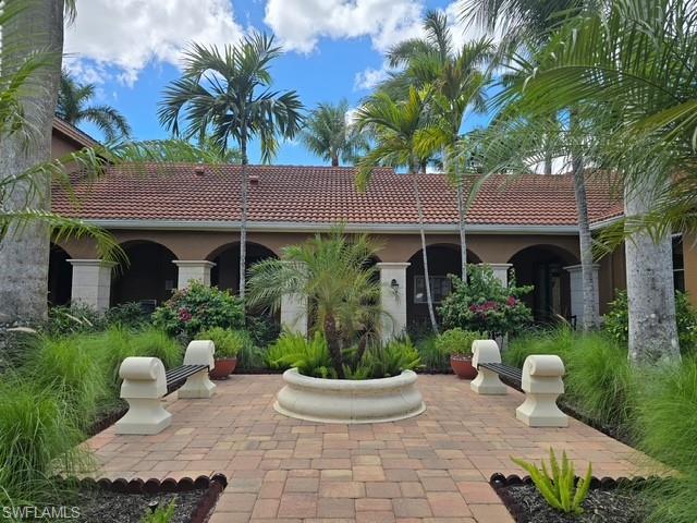 Back of property featuring a tile roof, stucco siding, and a patio