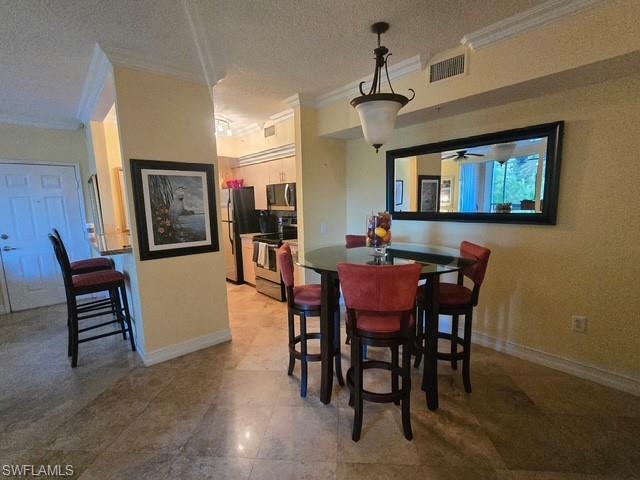 Dining area with crown molding, a ceiling fan, and a textured ceiling