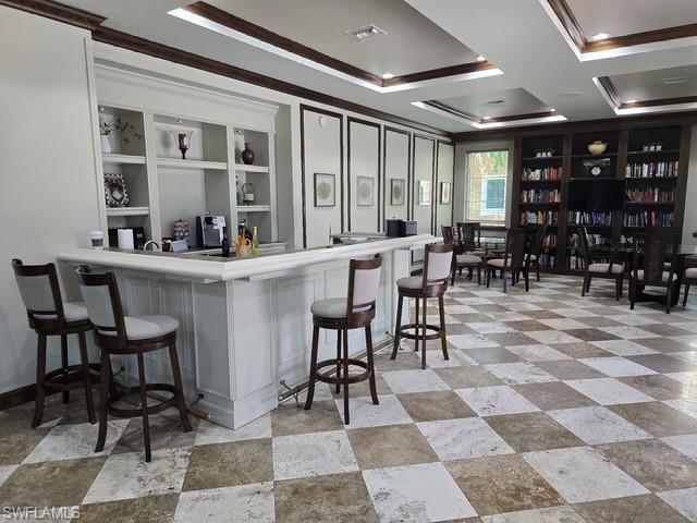 Bar with ornamental molding, light countertops, and coffered ceiling