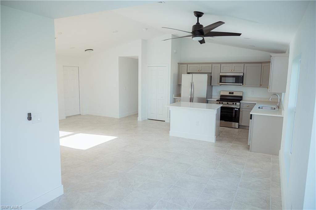Open-concept living space featuring a vaulted ceiling and tile flooring