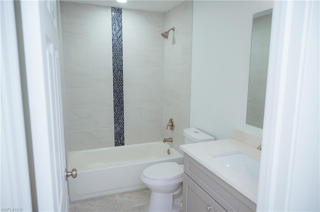 Contemporary bathroom featuring a tiled shower with decorative mosaic accent, brushed nickel fixtures, a light-toned vanity with an integrated sink, and recessed lighting