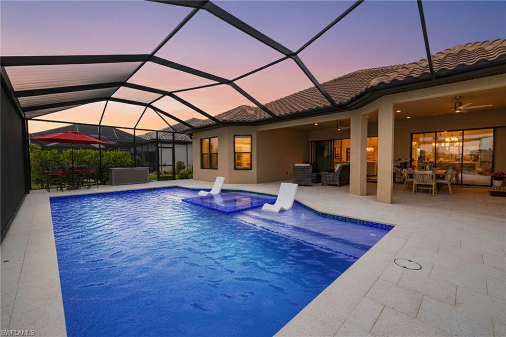 Outdoor pool with a sunroom, outdoor dining space, a hot tub, glass enclosure, and a patio area