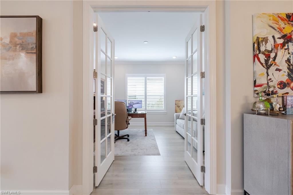 Hallway with french doors, an office area, light wood-style floors, crown molding, and recessed lighting