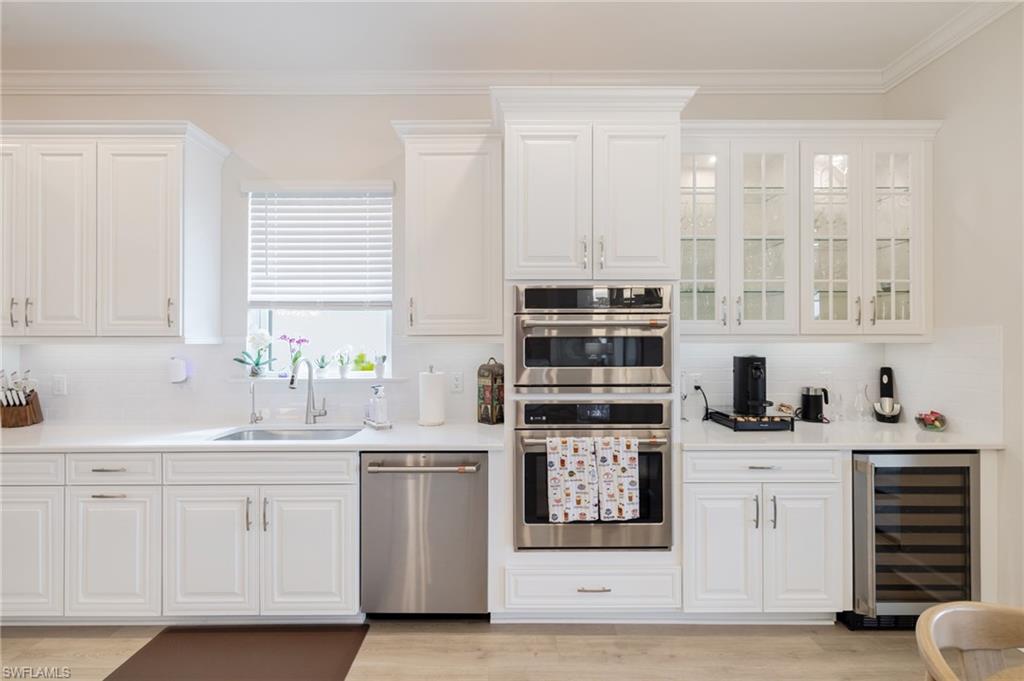 Kitchen featuring white cabinetry, stainless steel appliances, decorative backsplash, and ornamental molding
