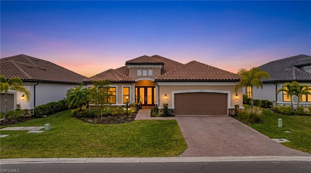 Mediterranean / spanish home with a garage, french doors, a front yard, stucco siding, and a tile roof