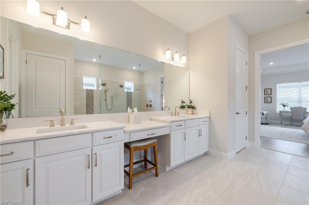 Ensuite bathroom featuring a stall shower, two vanities, healthy amount of natural light, and light tile patterned floors