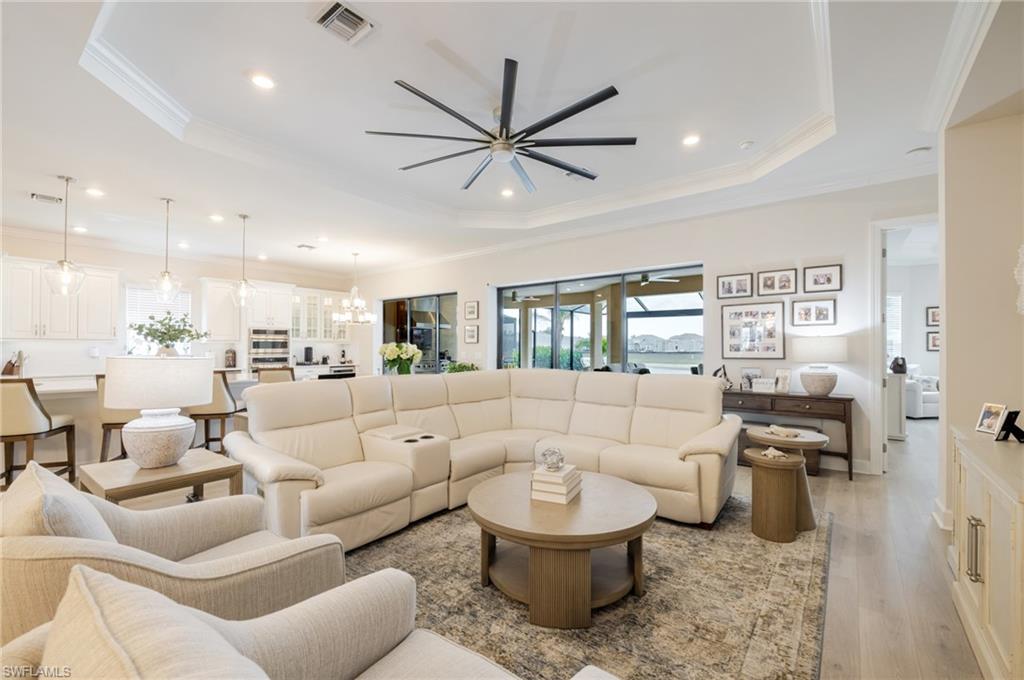 Living area with ceiling fan, crown molding, light wood-style flooring, and a chandelier